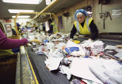 Workers on a Factory Assembly Line Sort Through Paper for Recycling